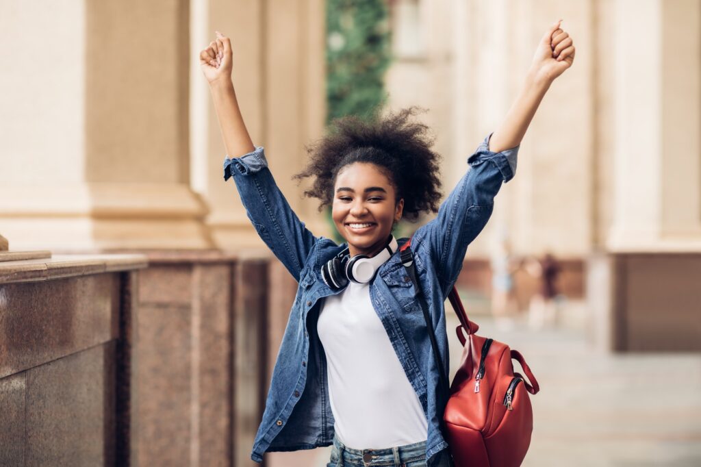 Happy African American Student Girl Shaking Fists Celebrating Success Outside